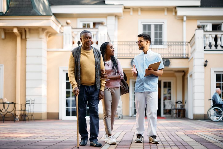 Senior living advisor walking with an older adult and family member outside a senior care community