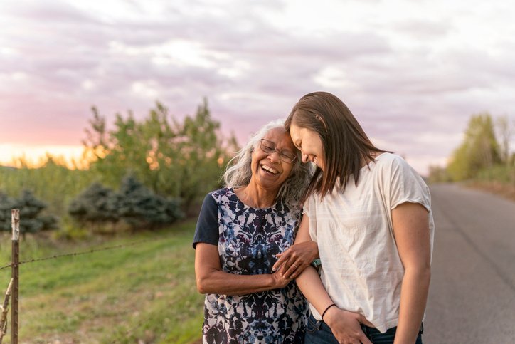 Adult daughter and her mother going for a walk in the common grounds of an assisted living facility.