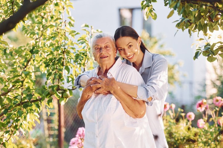 Young woman with her senior mother in the garden of an assisted living facility.