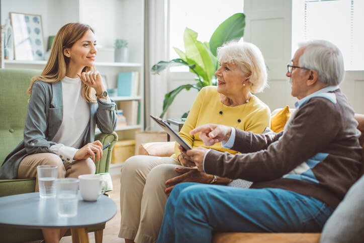 Senior couple meeting with a senior living advisor in a home or office setting, discussing care options
